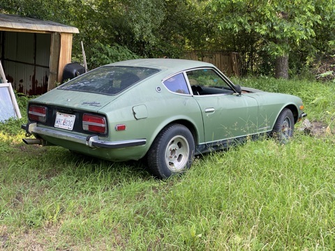 Green Datsun 240Z parked in the grass beside a shed