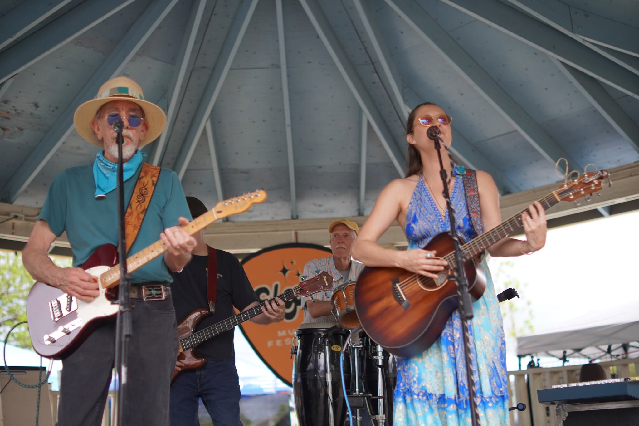Guitarists singing together beneath the gazebo roof
